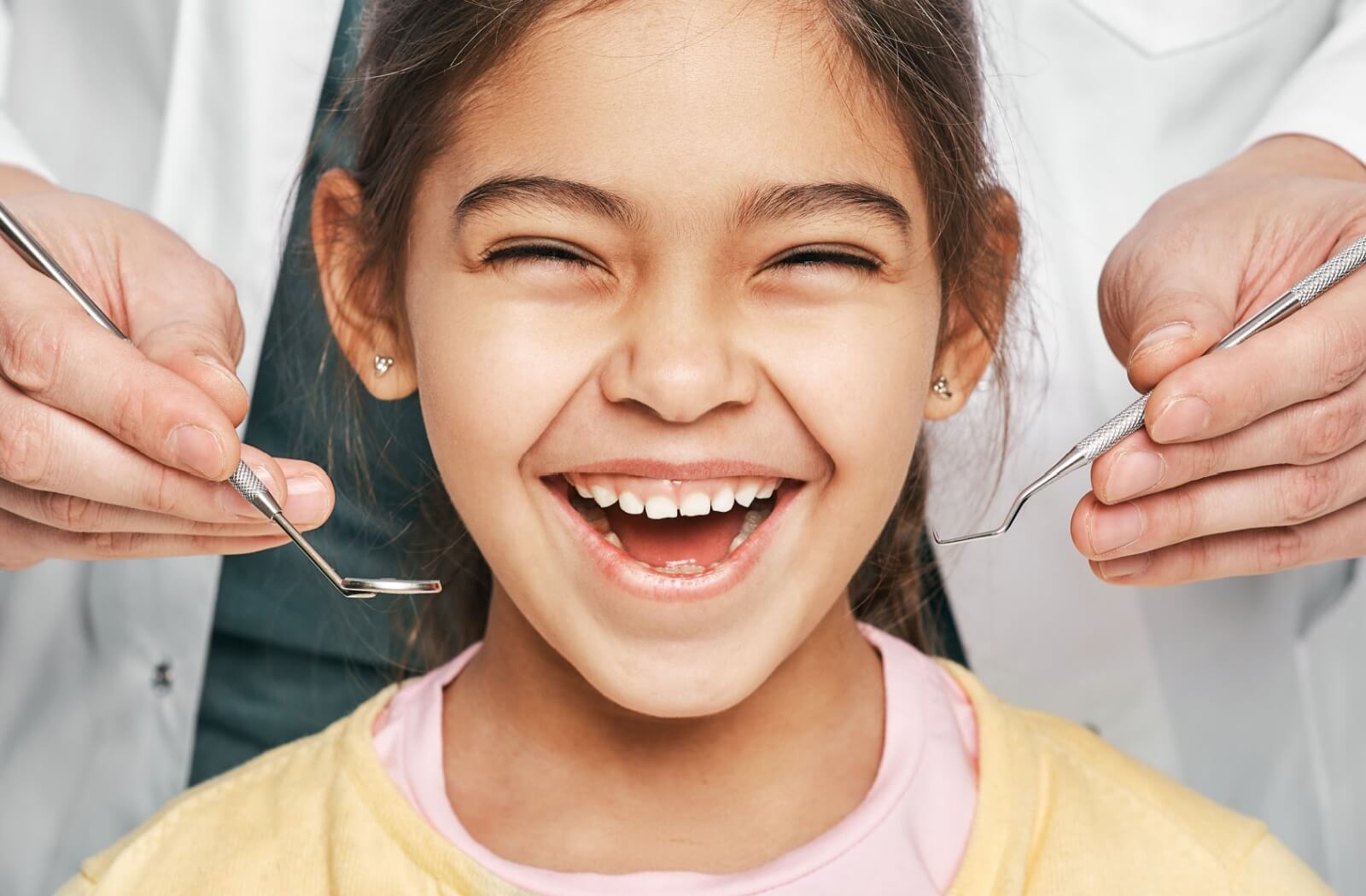 A smiling young child with a dentist getting ready to examine their teeth.
