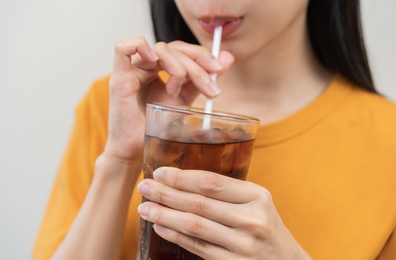 A person sips on a sugary soda through a straw.