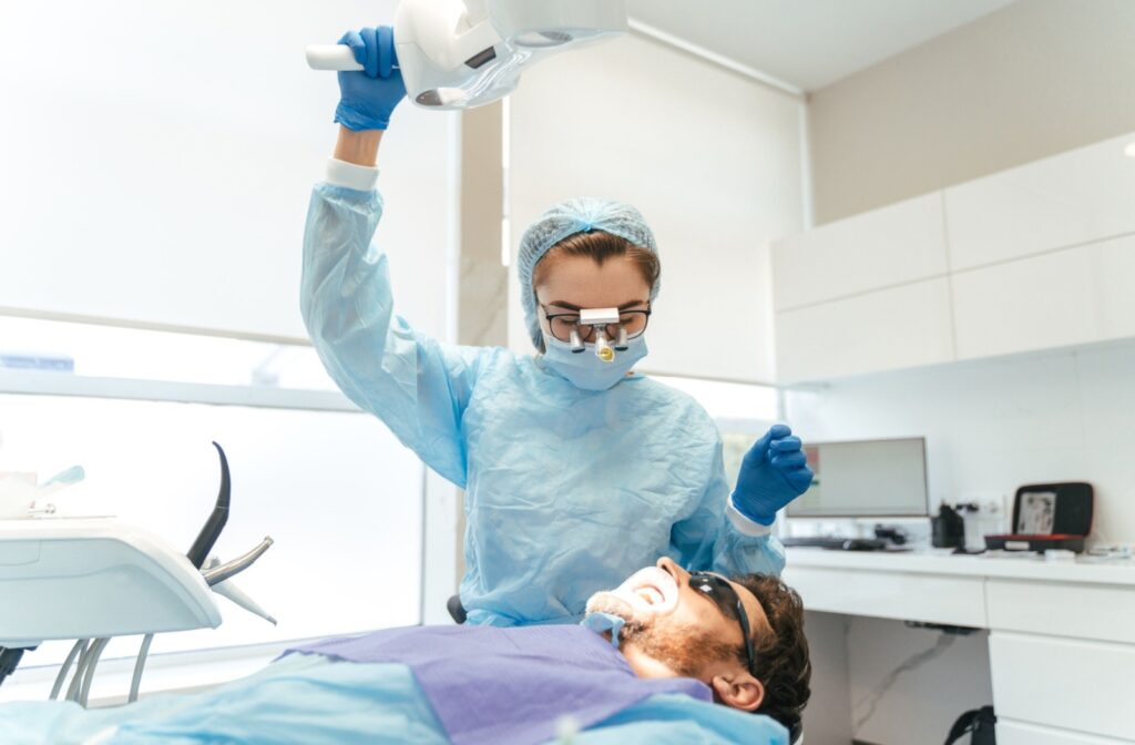 Dental professional preparing treatment for a relaxed patient in a dental chair during a sedation dentistry visit.
